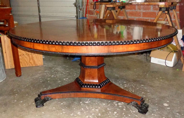 Rosewood circular table with ebonized egg and dart trim and lion's paw feet.