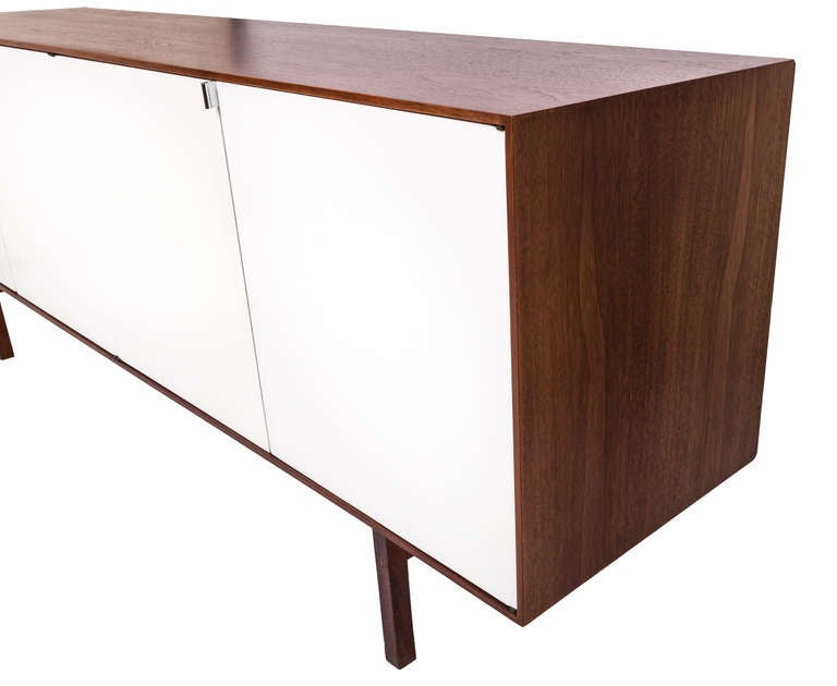 Florence Knoll designed credenza/cabinet for Knoll. 

USA, 1950s

Features dark walnut exterior and legs with white lacquered doors stainless drawer pulls. 

Very good condition with original label attached