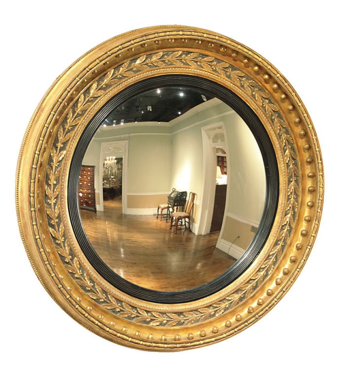 A fine late Regency large giltwood and ebonized convex mirror with laurel leaf and spherule border.
