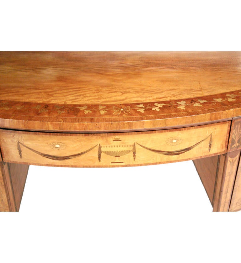 A  George III satinwood, mahogany and marquetry demi-lune sideboard.