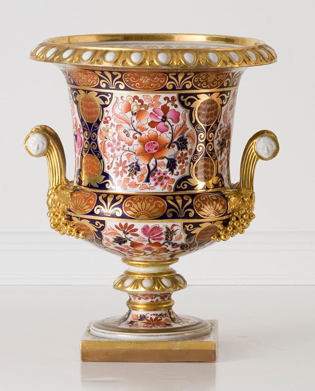 A pair of Worcester Flight, Barr & Barr urn-form ice pails decorated in the Imari palette, with gilt egg-and-dart rims and scrolled handles with classical masks and grape clusters, standing on plinth bases.