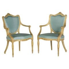 A pair of George III giltwood shield-back armchairs.