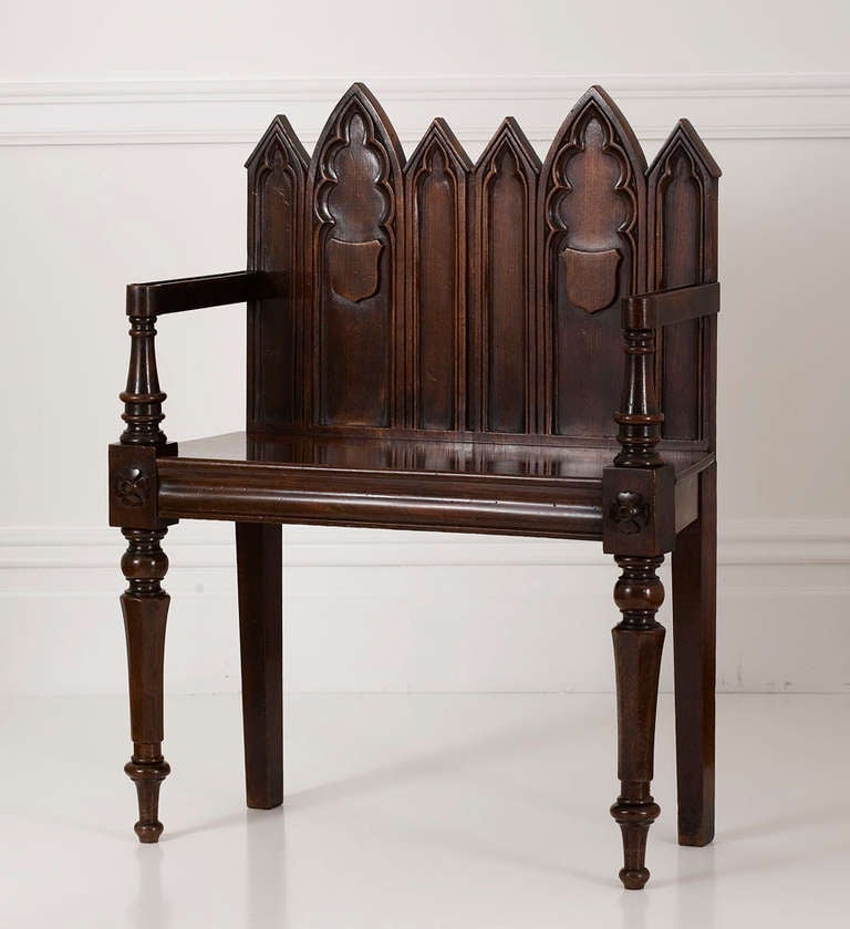 A charming small Regency Gothic-revival mahogany hall settee, the backrest with a picket and pointed-arch shaped top rail fitted with Gothic-arch molded panels and shields, raised on turned tapering octagonal legs headed by quatrefoils and ending in