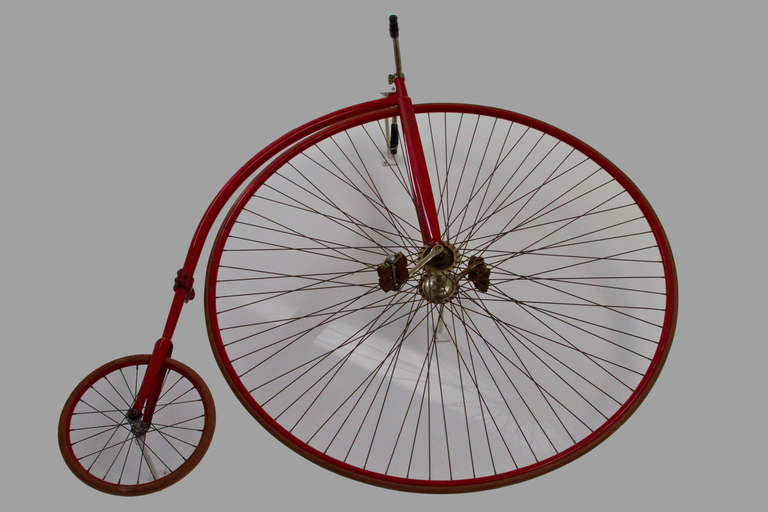 Beautifully proportioned, gently restored 19th century red high wheel bicycle with custom fabricated mounting points to enable dramatic wall mounting.  Strong yet whimsical accessory on cathedral wall.  The manufacturer is not certain therefore the