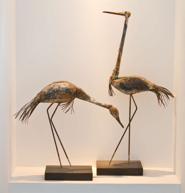 Early 20th century pair of heron decoys -- one feeding while the other keeps watch. Extraordinary dynamic and interaction between the figures.  Carved from wood with tin feathers.  From northern US or Canada.  The decoys are 41