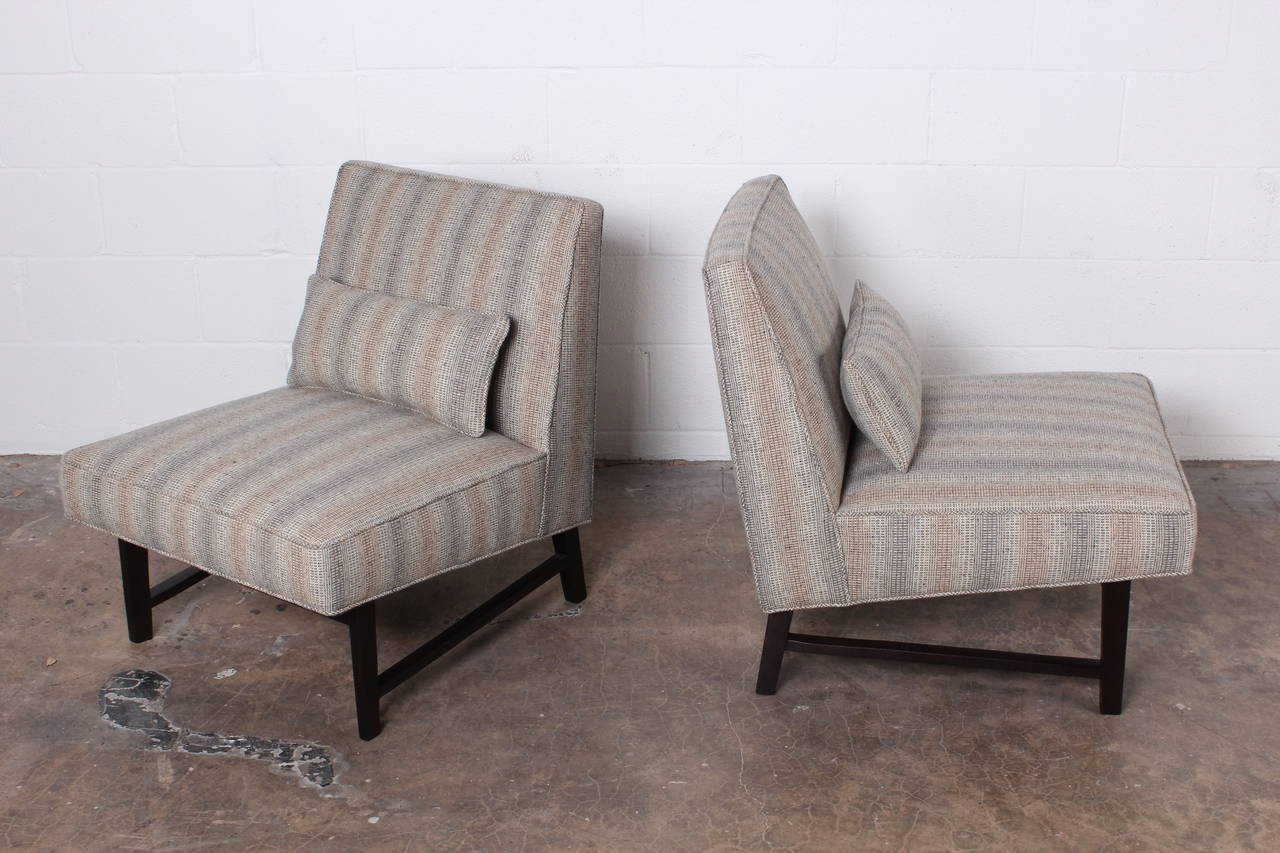 A pair of slipper chairs with mahogany bases and Maharam wool fabric. Designed by Edward Wormley for Dunbar.