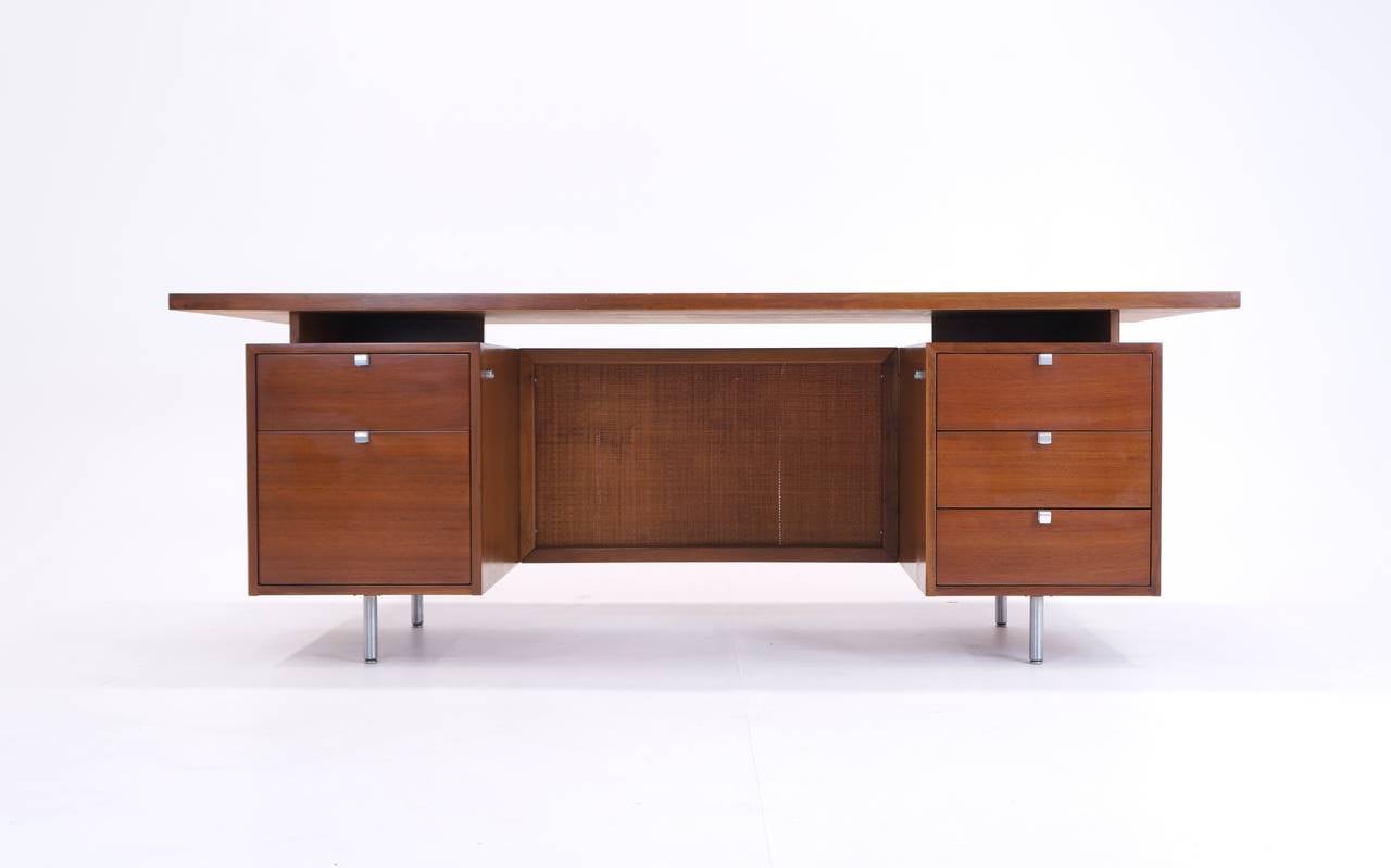 A walnut desk with cane panel and brushed steel legs. Designed by George Nelson for Herman Miller.