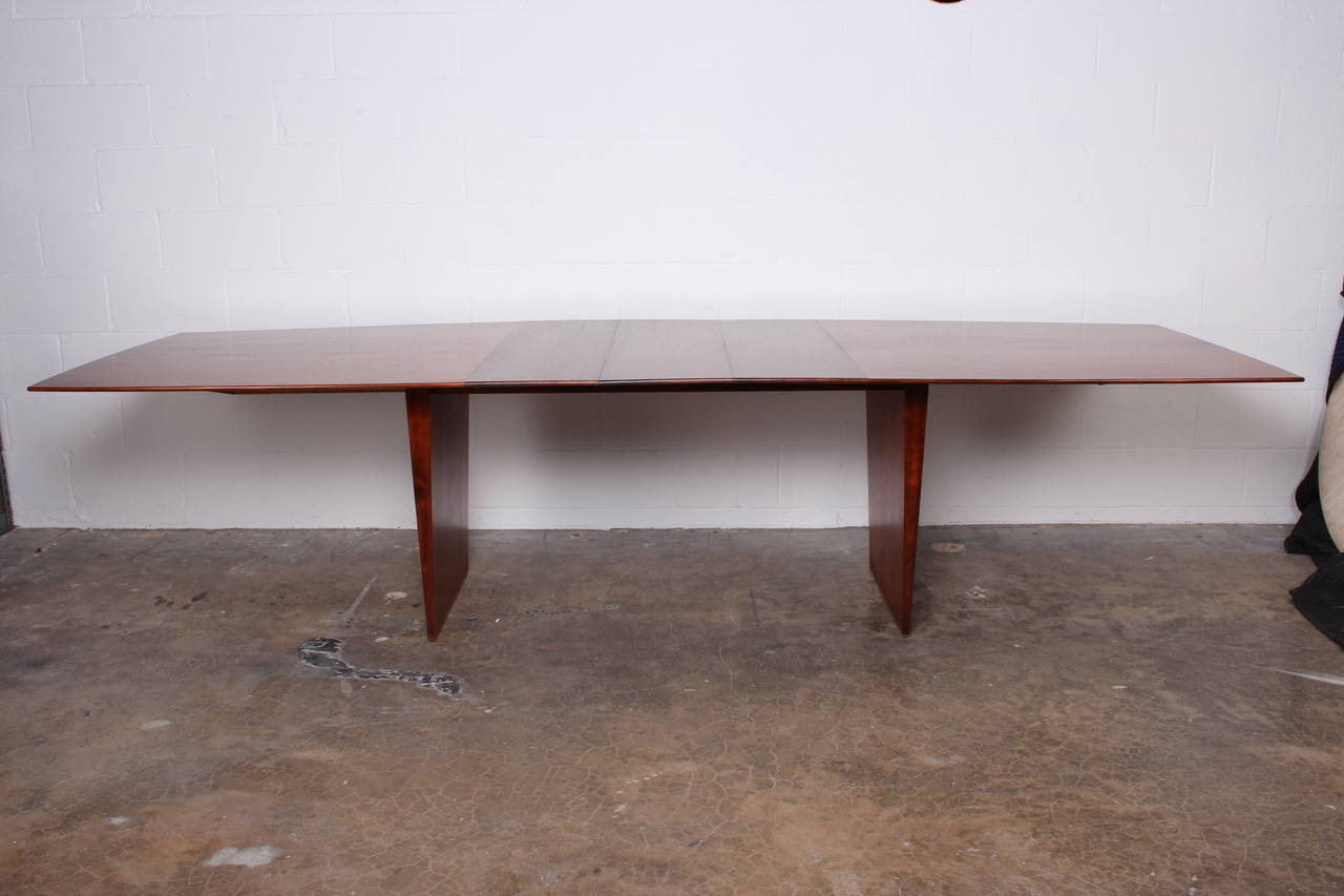 A large walnut fin-legged dining table with brass feet and three leaves.