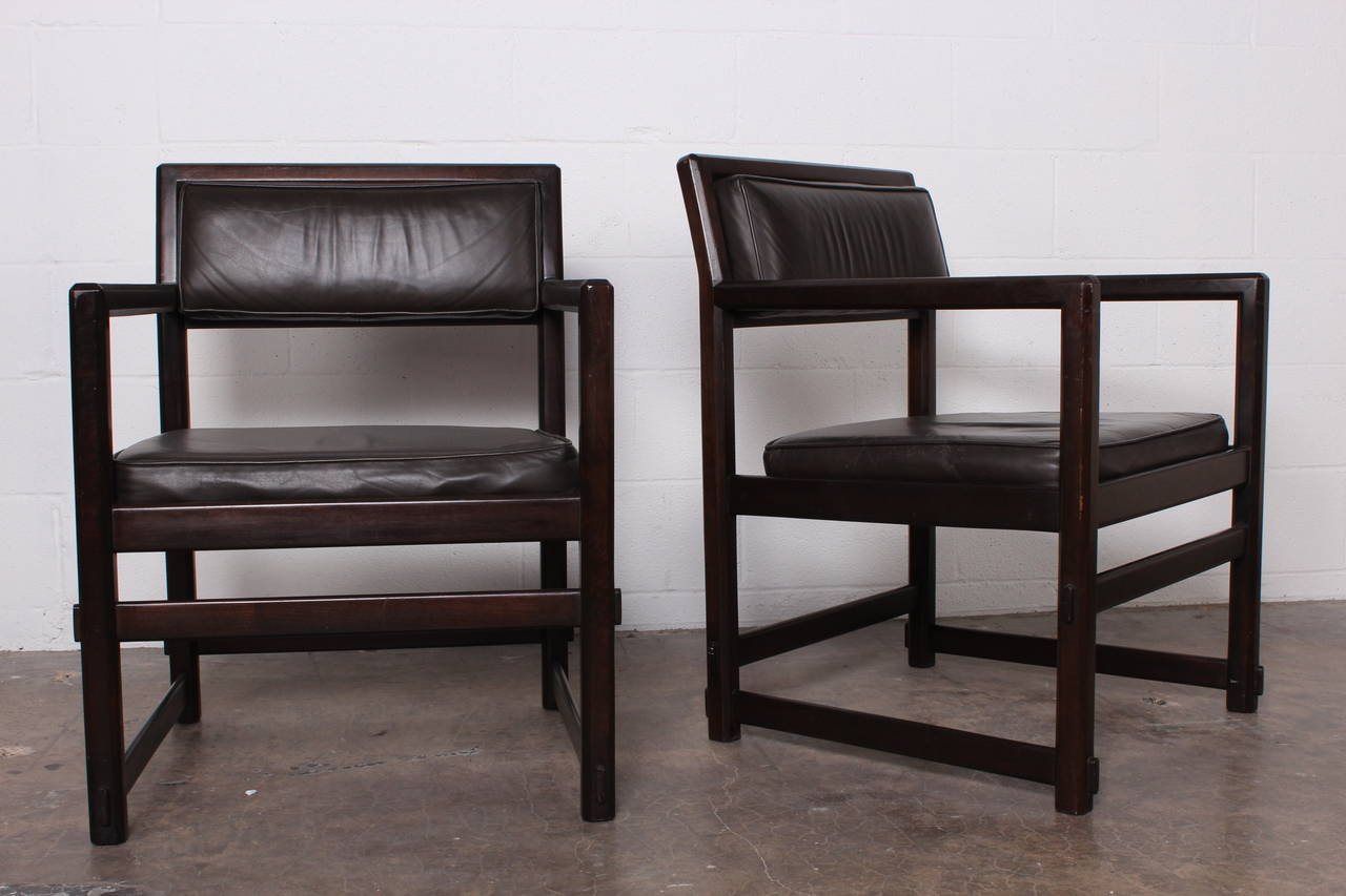 A pair of dark mahogany armchairs with original dark brown or black leather. Designed by Edward Wormley for Dunbar.