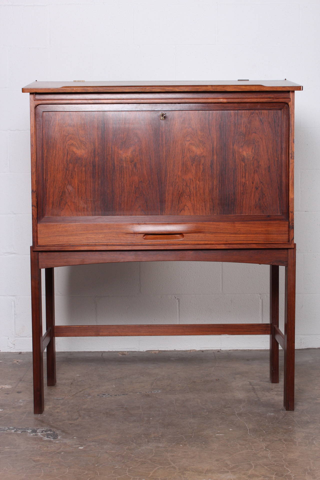 A beautifully crafted Danish rosewood drop front desk. The bottom drawer pulls out to support the desk top when down. Top lifts for storage as well.