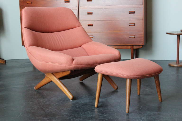 A lounge chair and ottoman on crossed solid teak legs by Illum Wikkelso.