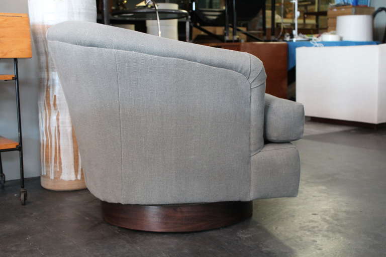 A pair of swivel chairs with walnut bases designed by Milo Baughman.