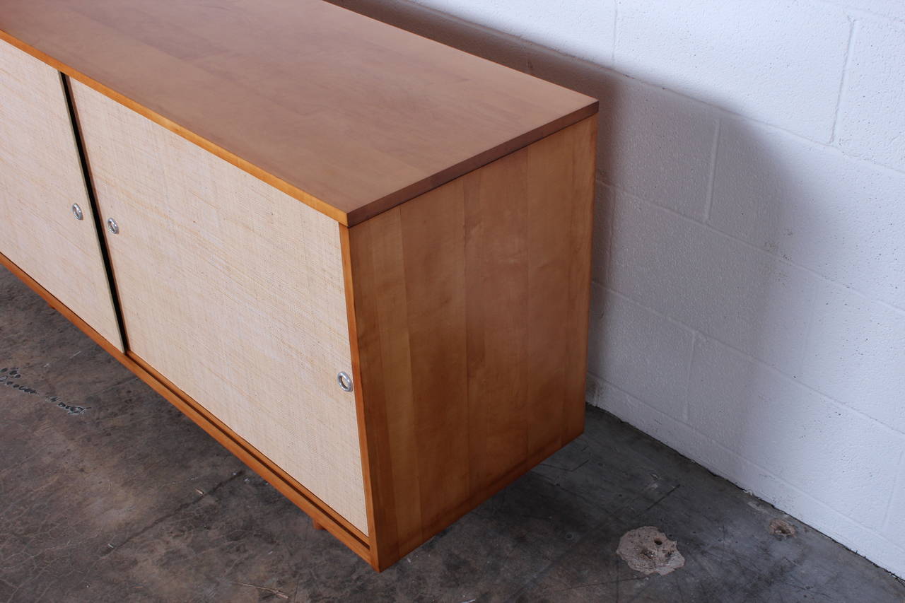A maple credenza with grass cloth doors. Designed by Paul McCobb for Winchendon.
