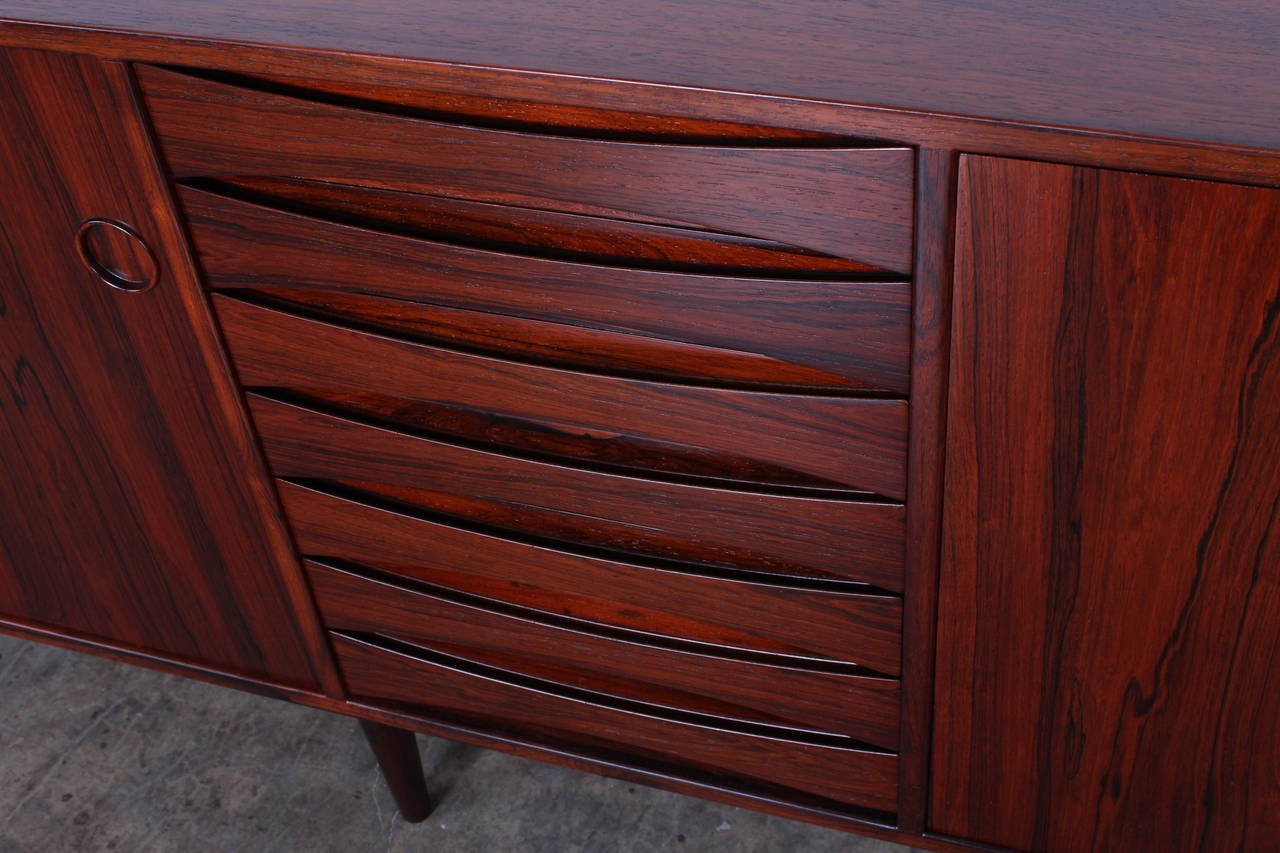 A large rosewood cabinet with drop down bar and reversible sliding doors. Designed by Arne Vodder for Sibast.