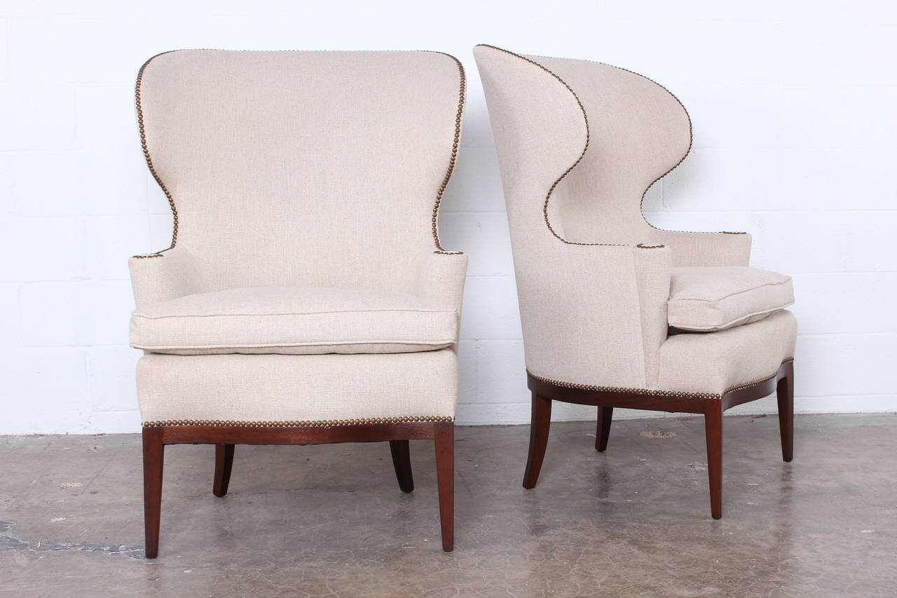 A pair or early mahogany based wingback chairs designed by Edward Wormley for Dunbar.