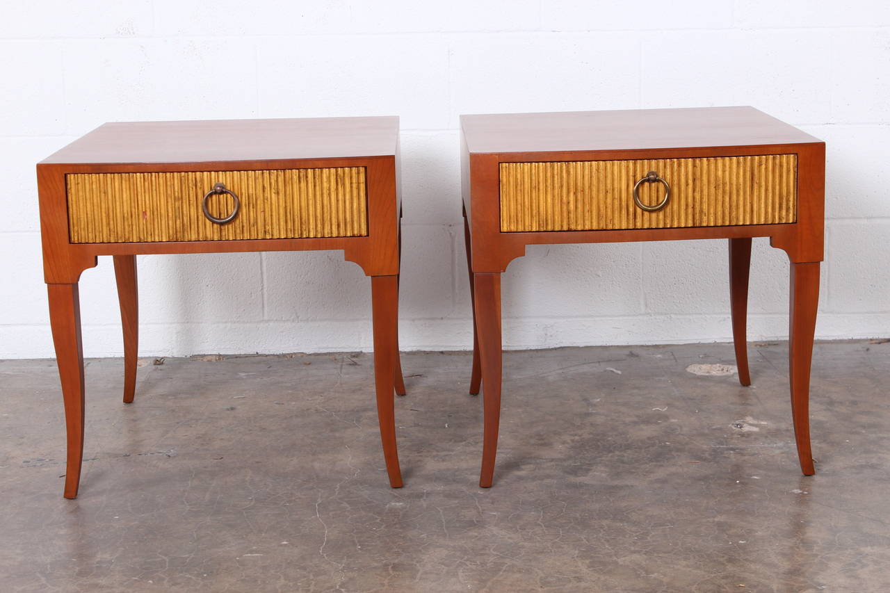 A beautifully scaled pair of end tables with gold leafed drawer fronts by Baker.