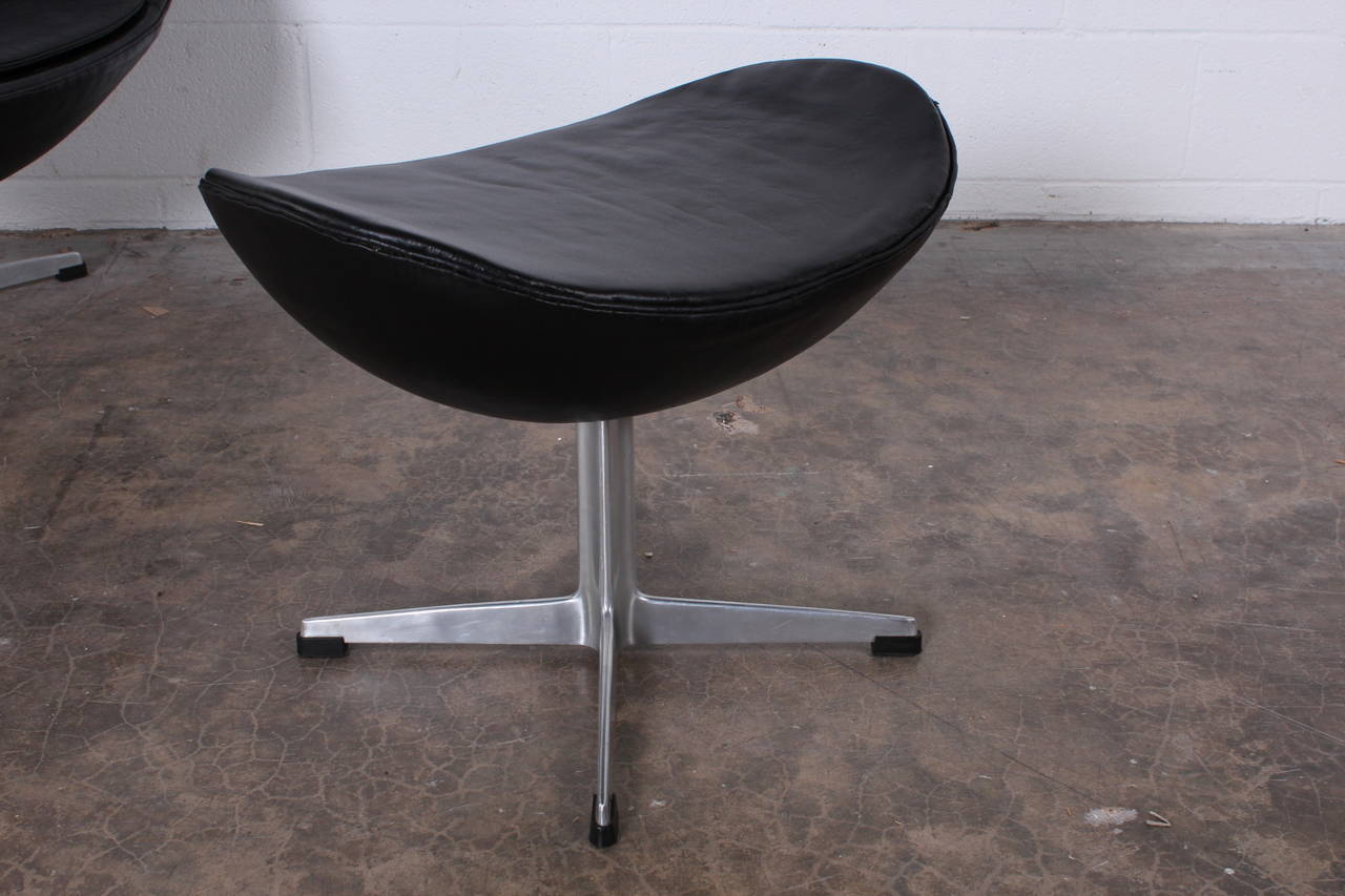An egg chair and ottoman in original black leather. Designed by Arne Jacobsen for Fritz Hansen.