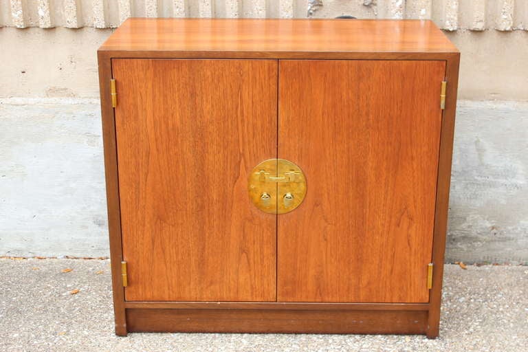 A walnut cabinet with adjustable shelves and brass hardware. Designed by Edward Wormley for Dunbar.