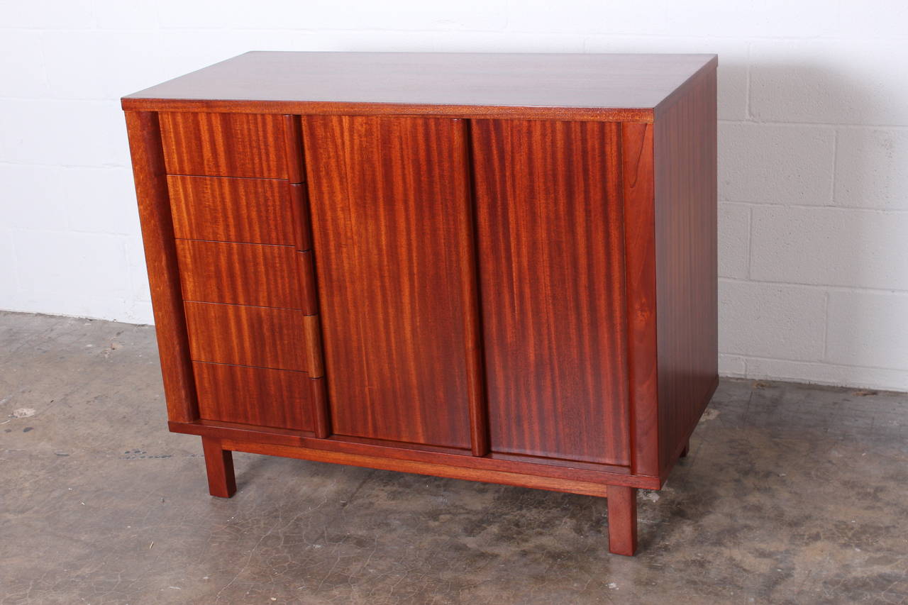 A mahogany chest with five drawers and a bifold door concealing two cane shelves. Designed by Edward Wormley for Dunbar.