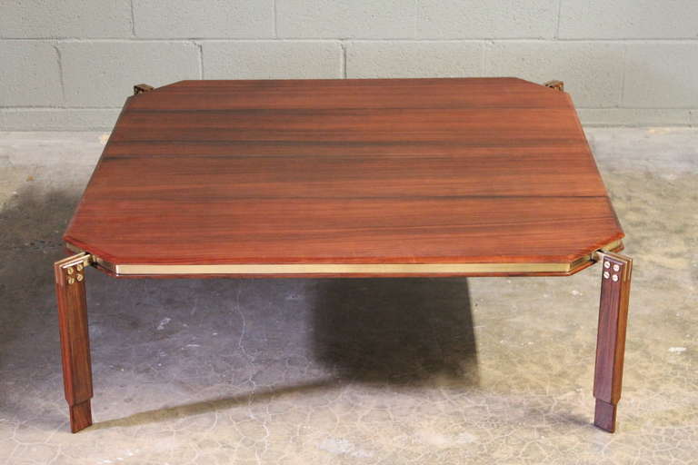 A beautifully made rosewood cocktail table with brass hardware and floating top.