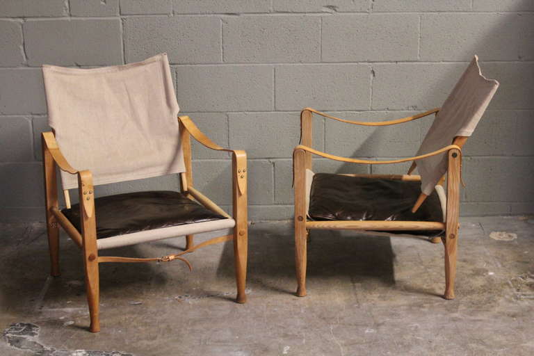 A pair of canvas and leather safari chairs with oak frames. Designed by Kaare Klint for Rudolf Rasmussen.