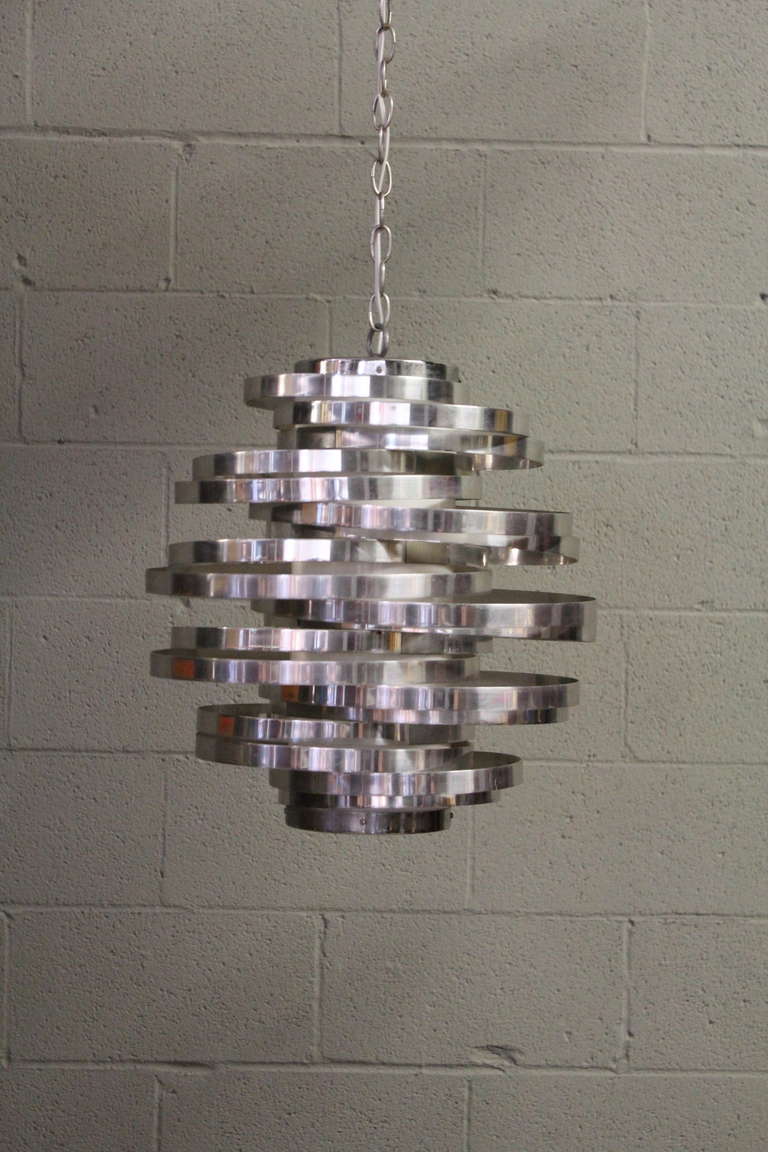 A beautifully lit aluminum ring chandelier designed by Max Sauze.