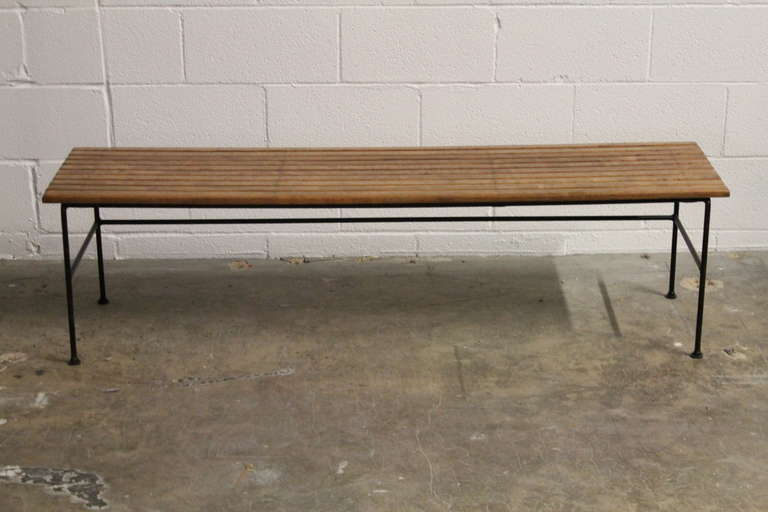 A slat table/bench with three rush stools that can be stored underneath. Designed by Arthur Umanoff for Raymor.