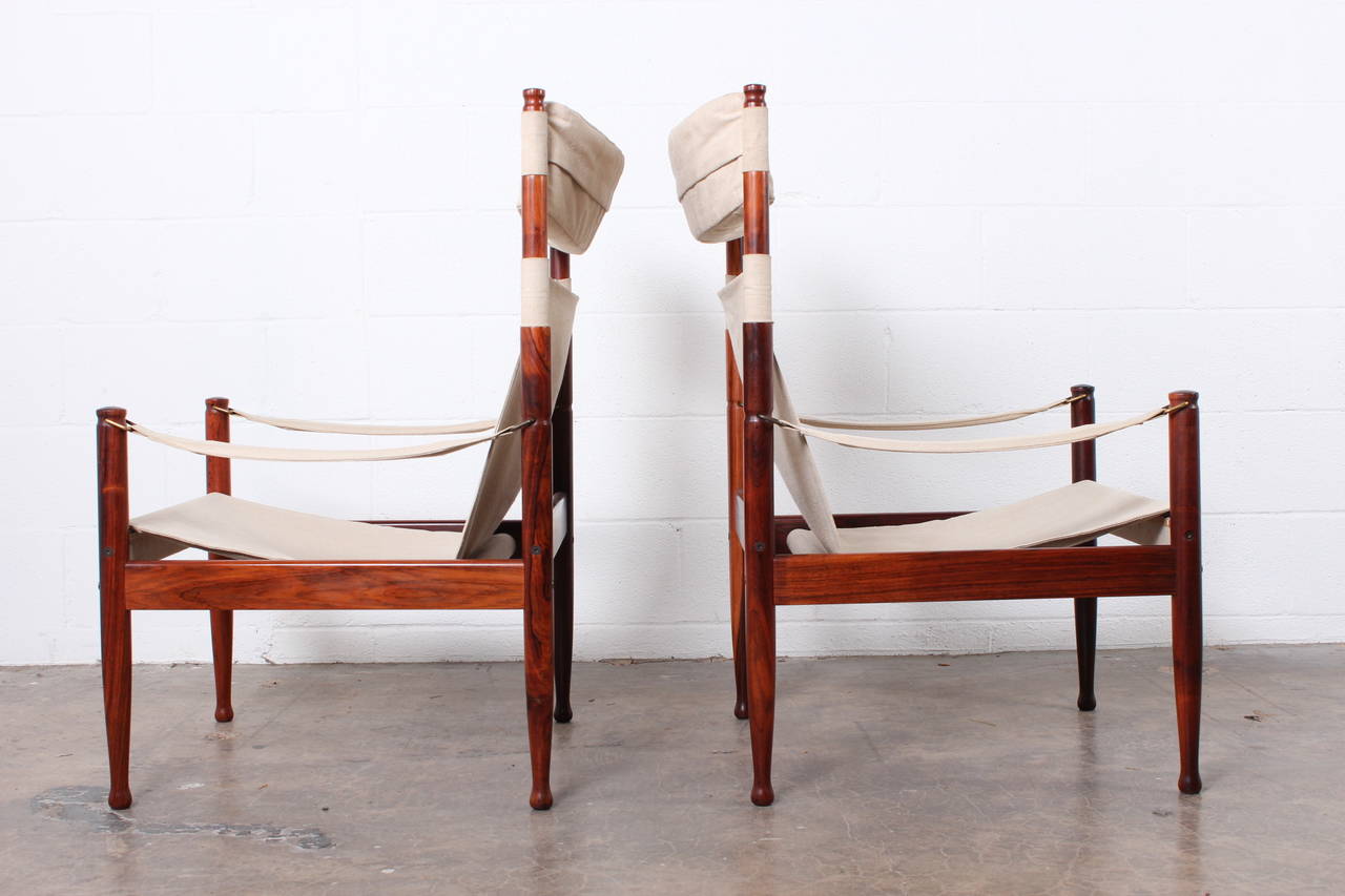 A pair of high back rosewood and canvas safari chairs designed by Niels Eilersen.