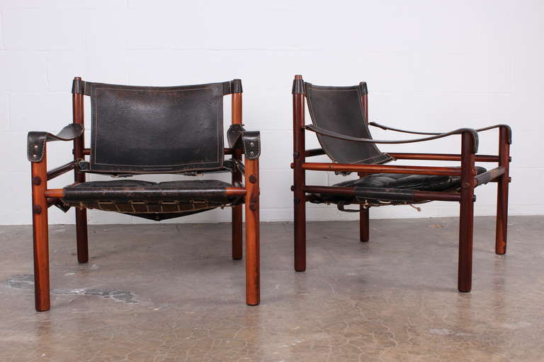 A beautifully patinated pair of solid rosewood and black leather safari chairs designed by Arne Norell.