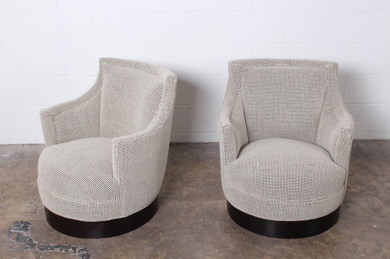 A petite pair of early swivel chairs on walnut bases upholstered in Maharam Monks wool. Designed by Edward Wormley for Dunbar.