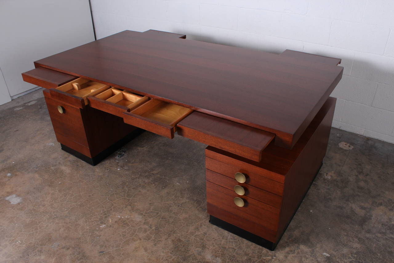 A rare, floating top mahogany desk designed by Gilbert Rohde for Herman Miller. Top has pull out writing surfaces on both sides of desk.