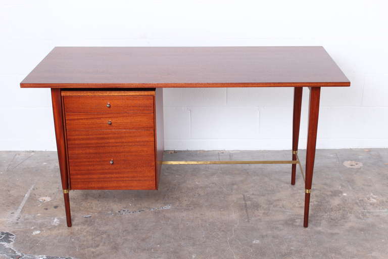 A mahogany and brass desk designed by Paul McCobb for Calvin.