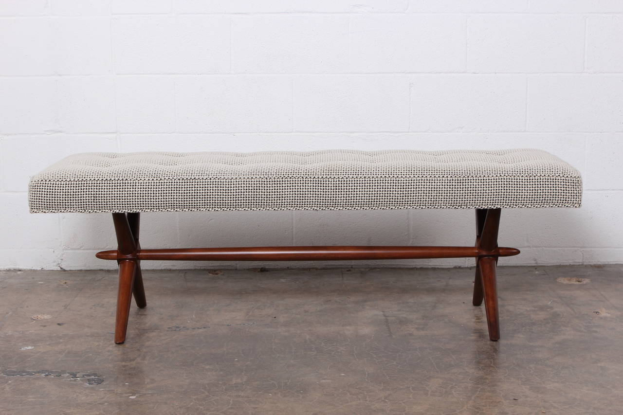 A walnut bench upholstered in 