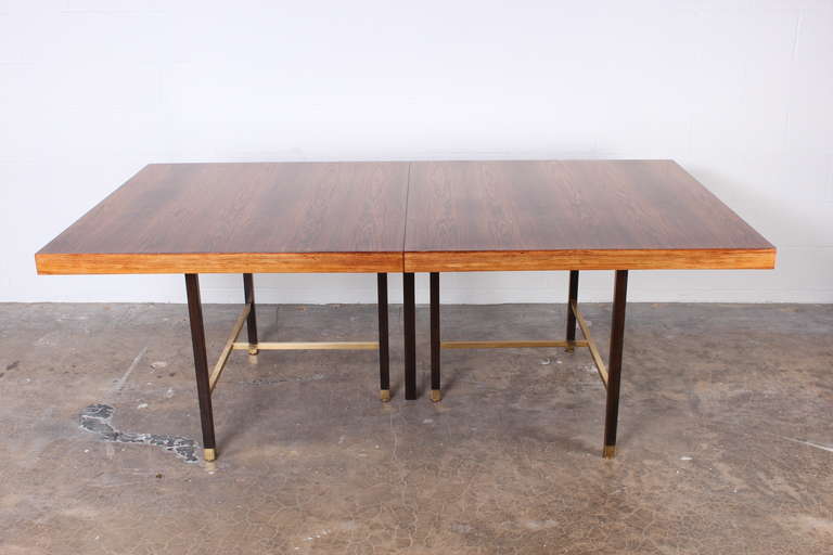 A monumental dining table with bleached rosewood top, mahogany base and brass stretchers. Includes four book matched 16