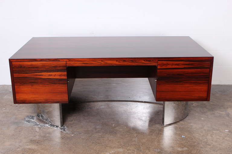 A beautifully grained rosewood executive desk with curved chrome base.
