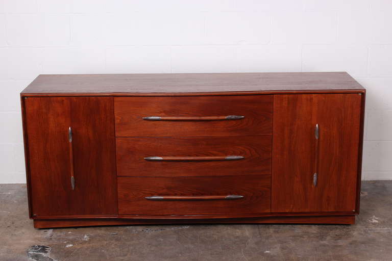 A bowed front walnut  credenza with silver hardware. Designed by T.H. Robsjohn-Gibbings for Widdicomb.