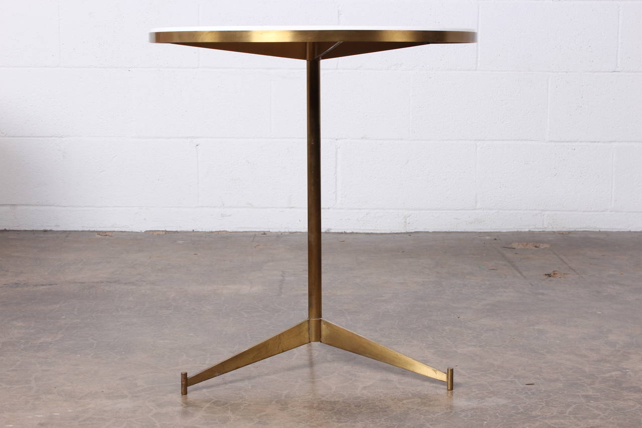 A brass side table with inset white glass top. Designed by Paul McCobb.