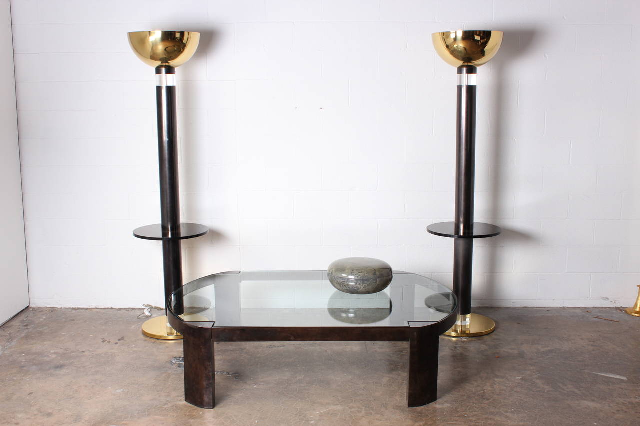 A custom pair of gunmetal, polished brass and lucite floor lamps with attached glass tables. Designed by Karl Springer.