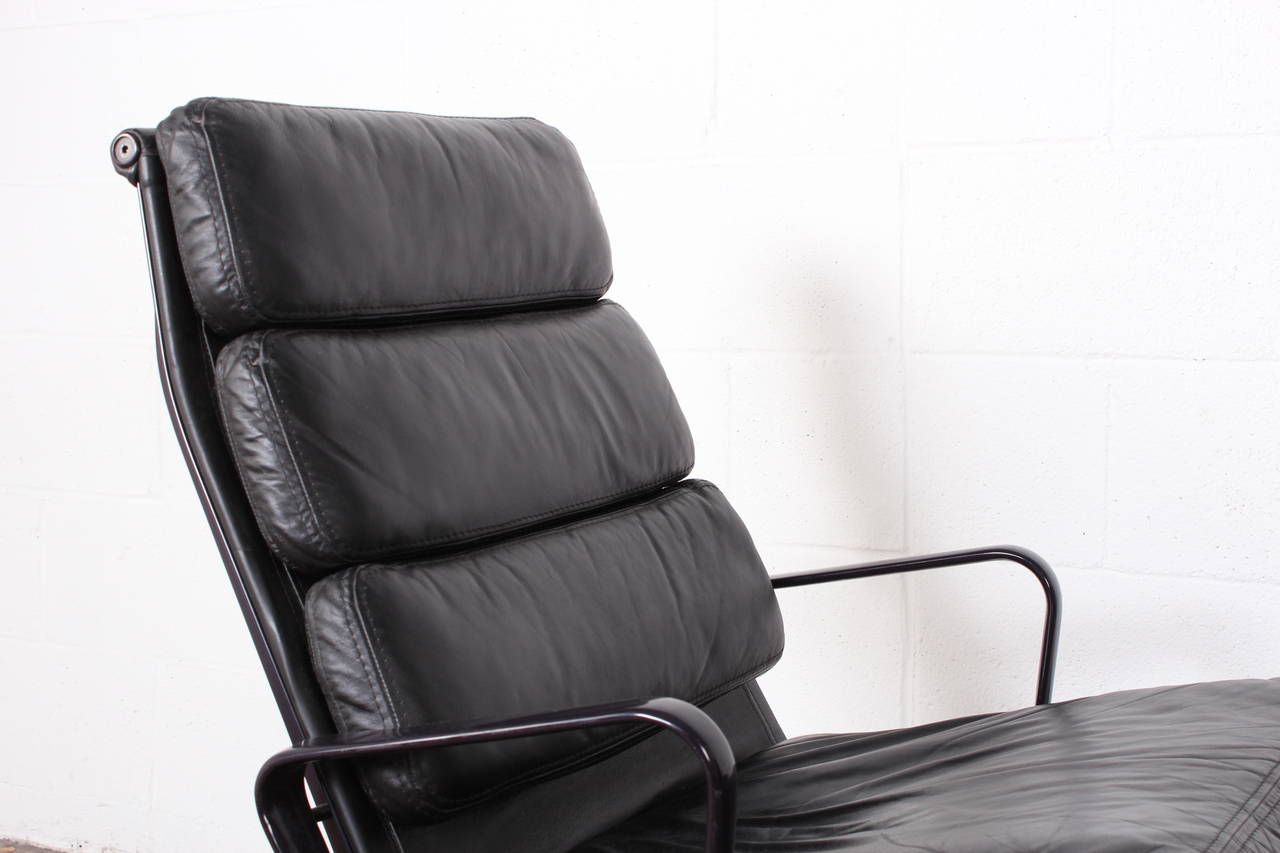 A pair of swiveling high-back lounge chairs with black leather and eggplant frames. Designed by Charles Eames for Herman Miller.