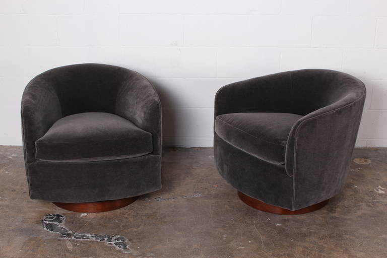 A pair of walnut based swivel/rocking chairs upholstered in grey mohair. Designed by Milo Baughman.