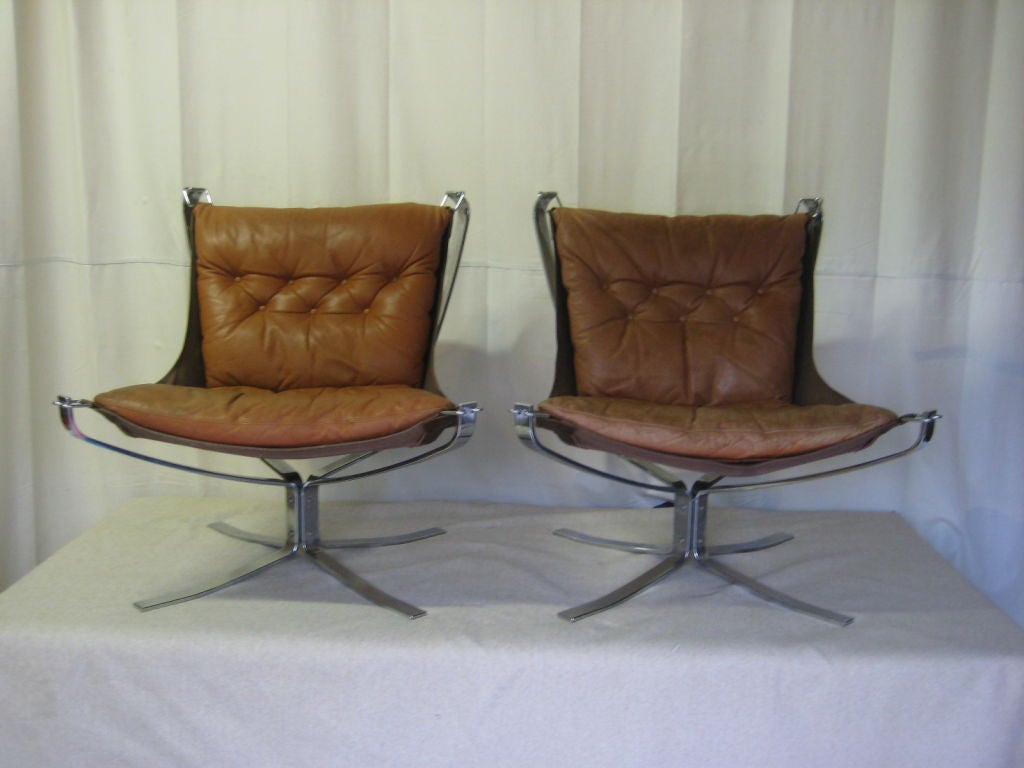 A pair of Falcon chairs designed by Sigurd Russell.  Chrome frames, canvas backs and leather cushions. Leather has a nice patina.  One chair has a bit more patina than the other but still show nicely together.