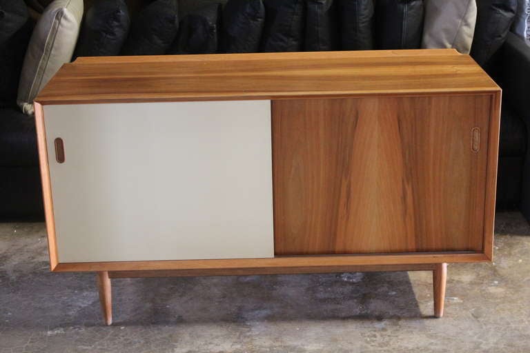 A bleached walnut cabinet with reversible sliding doors (walnut on one side and off-white lacquer on the other) Designed by Arne Vodder for Sibast.