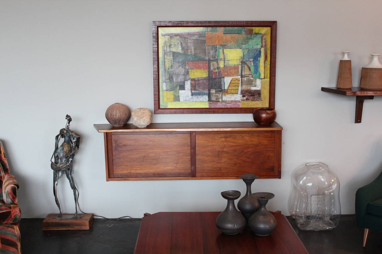 A walnut wall-mounted cabinet by George Nakashima, circa 1958. Cabinet features two sliding doors, dovetailed joinery, expressive free-edge and left over hang. Sold with copy of the original purchase card.