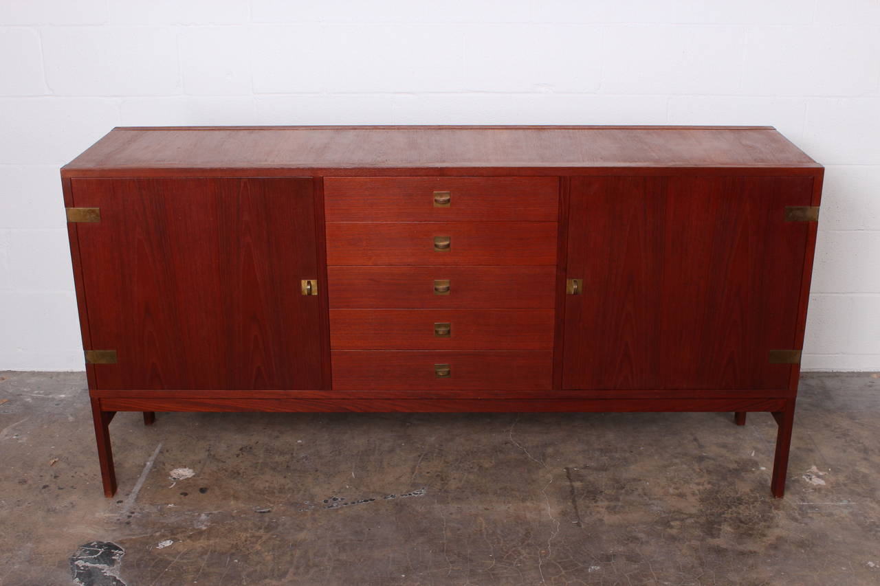 A teak cabinet with brass hardware by France and Sons.
