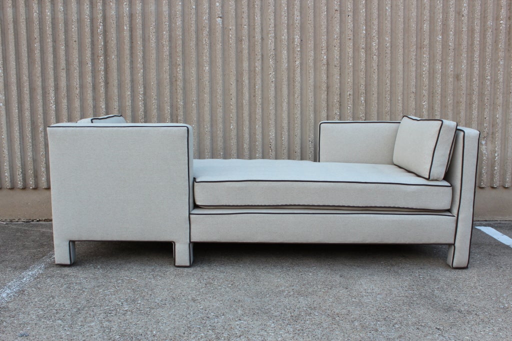 A classic Tete-a-Tete form upholstered in natural linen and leather piping with down pillows. Although this is a slight variation from the original design it has Dunbar construction and was acquired from an estate with other Dunbar furniture.
