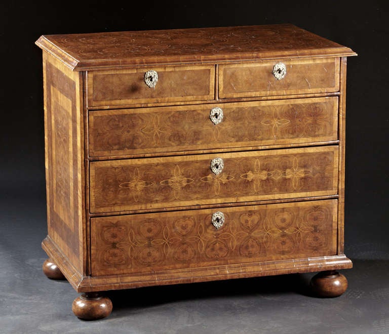 An early Georgian, George I, oyster veneered walnut chest of drawers. The geometric line inlaid top with oyster veneers and molded edge top above two split drawers and three graduated drawers and raised on turned feet. A careful choice of veneers