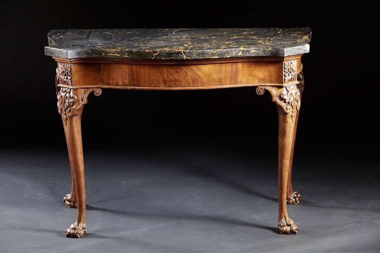 A George III marble-top serpentine console table in the manner of Gillows with cabriole legs ending in claw feet. The original thick, chiseled black and gold marble rests on a conforming serpentine frame with canted corners having carved rosettes