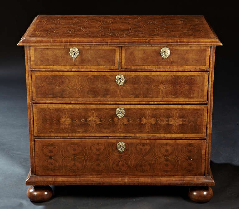 An early Georgian, George I oyster veneered chest of drawers. The geometric line inlaid top with oyster veneers and molded edge top above two split drawers and three graduated drawers and raised on turned feet.  A careful choice of veneers and the