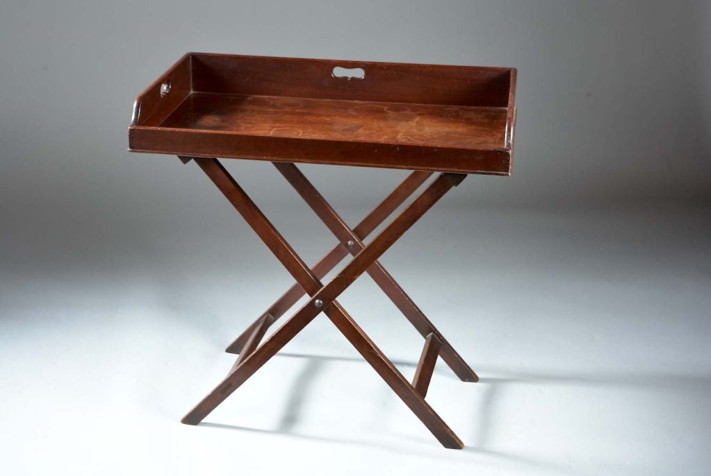 A Chippendale butler's tray on stand. The dovetailed tray with cut-out handles is supported by a simple scissor 