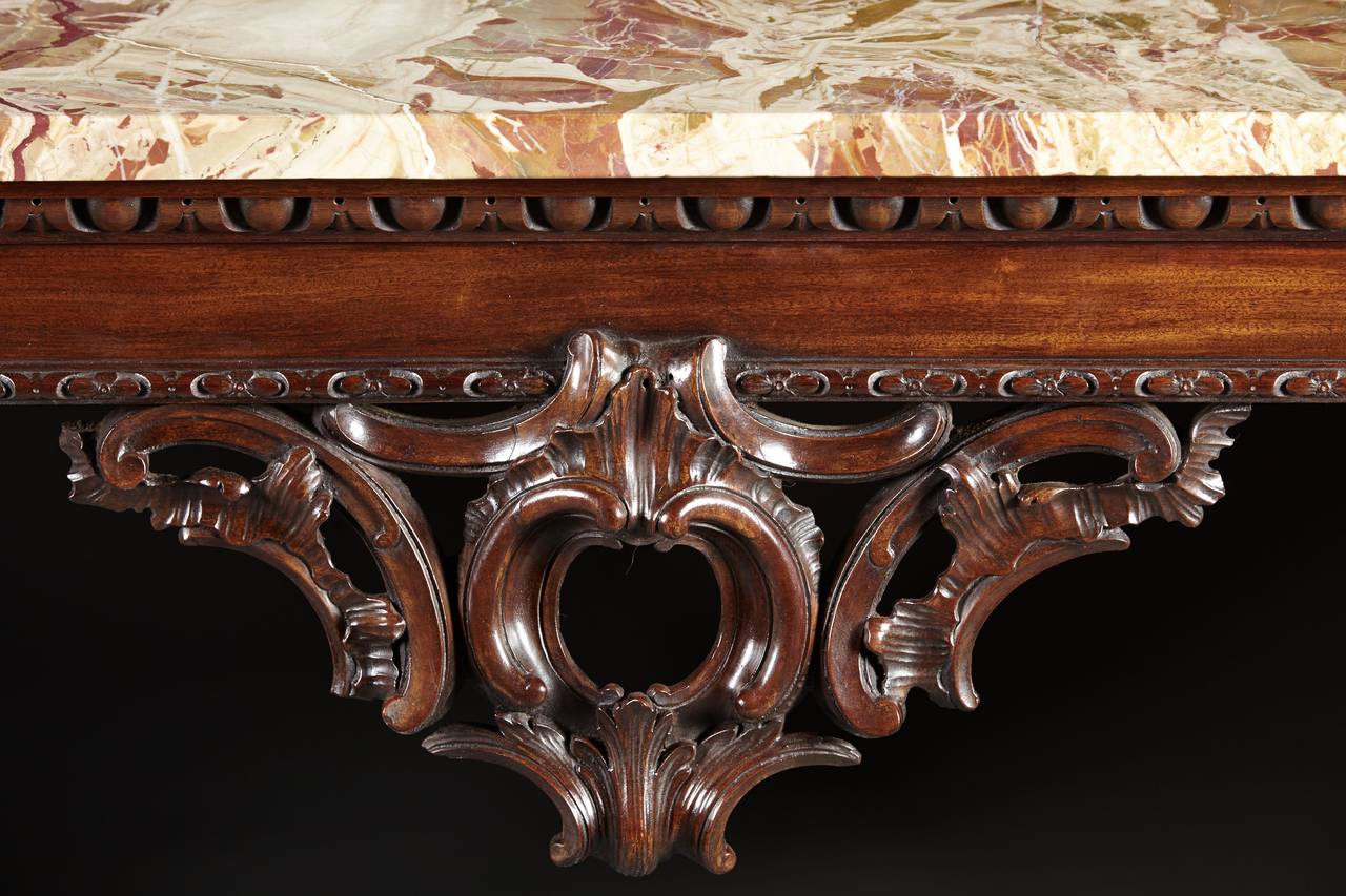 A very Fine mahogany George II console table with marble top. The exuberantly carved cabriole legs with foliate carved knees and realistic lion paw feet support a frame with egg and dart molding and a wonderfully carved central pendant. English,